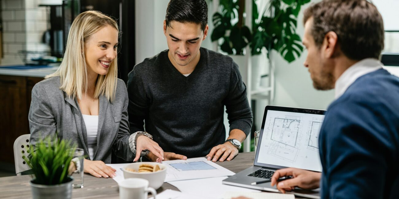 Happy couple consulting with real estate agent about housing plans on a meeting.